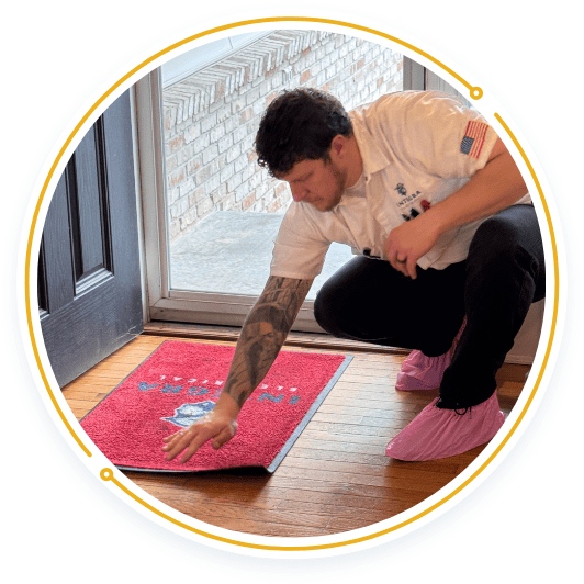 Electrician wearing pink shoe covers places a branded Integra Electrical mat at the front door to protect the home’s floors.