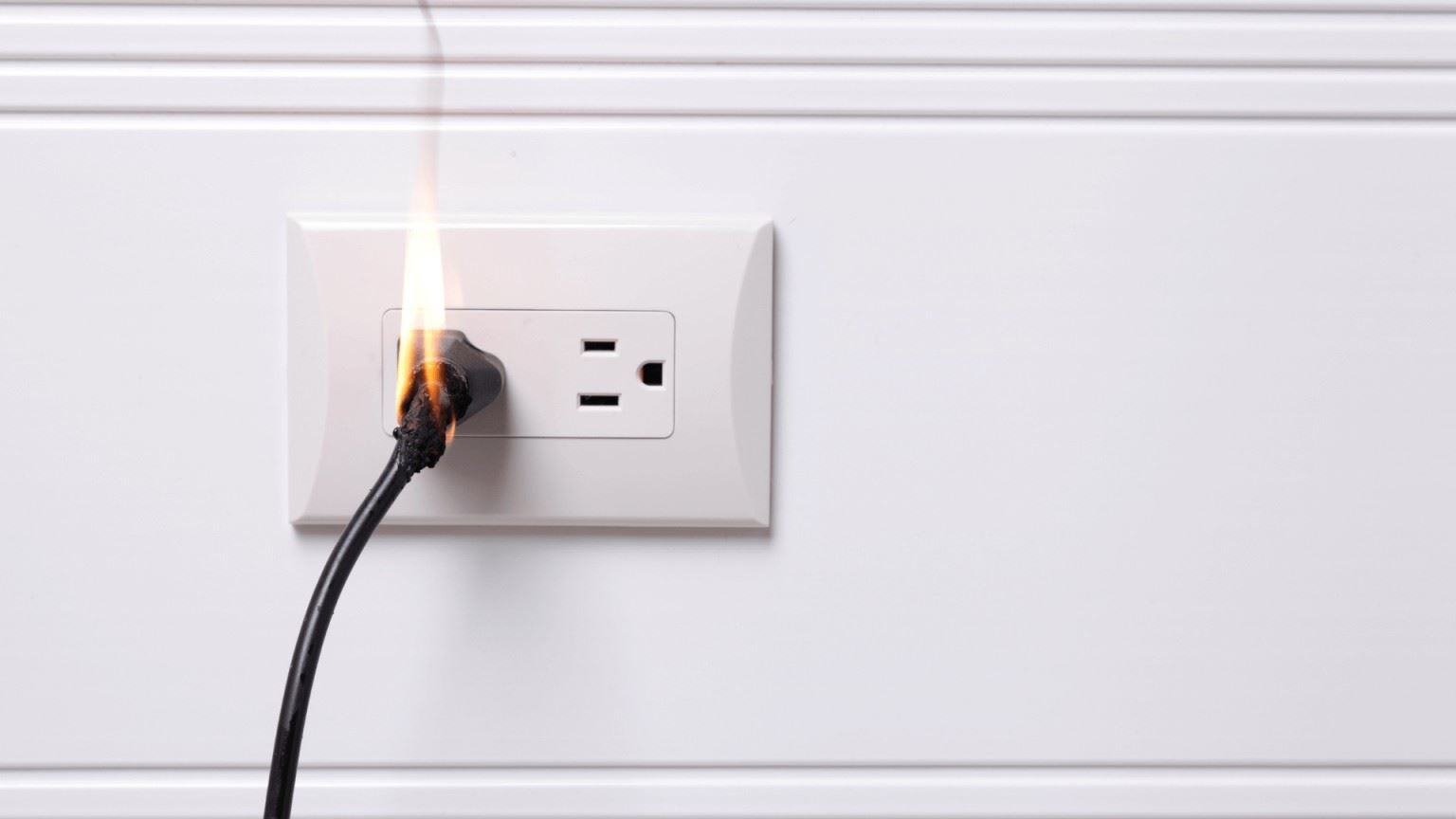 A cord plugged into an outlet that's on fire