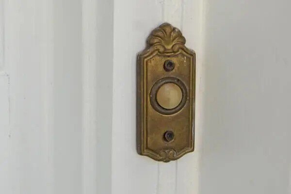 An ornate, gold-colored, vintage doorbell