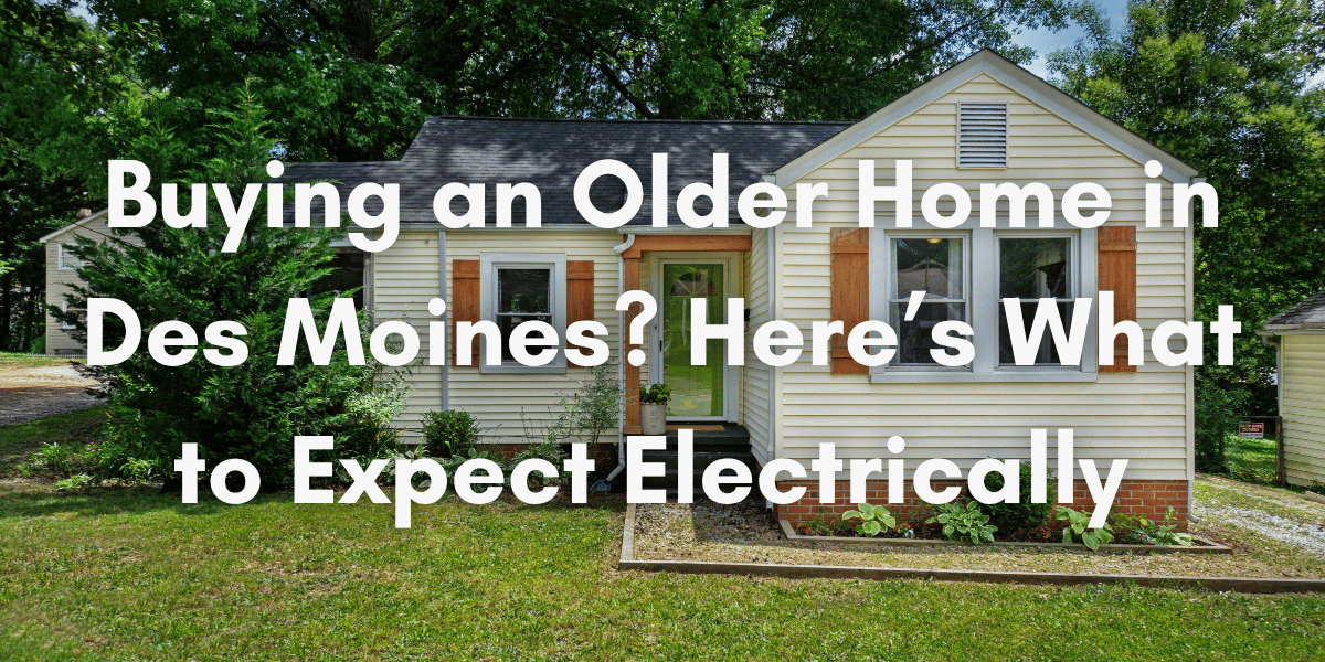 A small older single-story home in a leafy Des Moines neighborhood with large trees and a front lawn. White overlay text reads: “Buying an Older Home in Des Moines? Here’s What to Expect Electrically.”