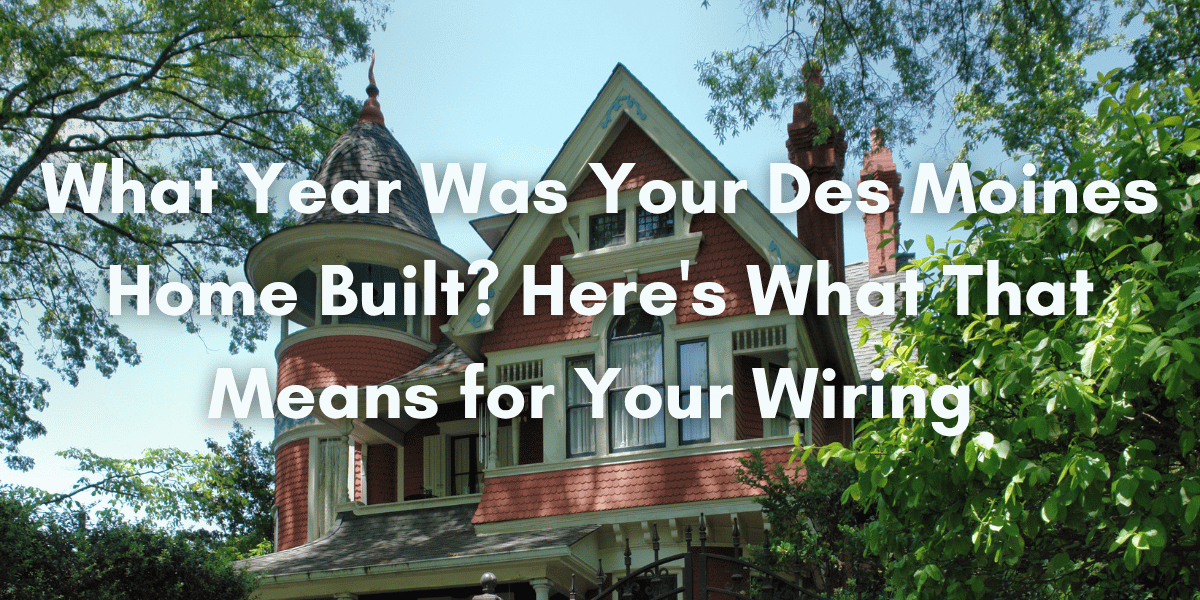Historic Victorian-style home in Des Moines surrounded by trees and greenery, with large white overlay text reading: “What Year Was Your Des Moines Home Built? Here's What That Means for Your Wiring.”
